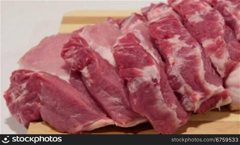 Sliced fresh pork meat on wooden cutting board close-up