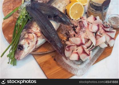 Sliced frozen raw fish from whitefish species - white salmon, whitefish, decorated with whole fishes, ice, lemon and greens. Siberian cuisine. Sliced frozen raw fish from whitefish
