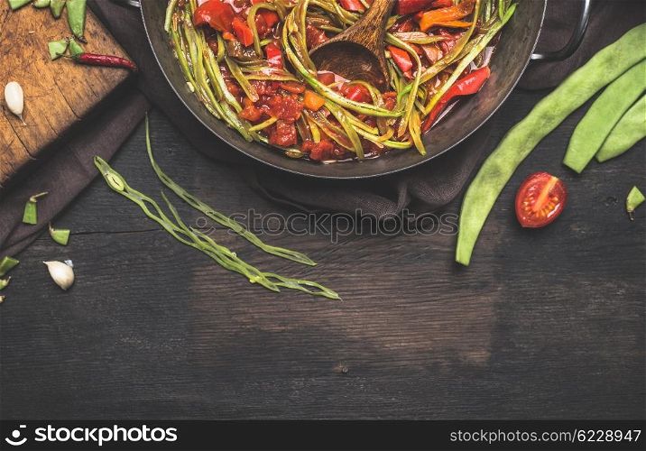 Sliced green French beans with tomatoes sauce on dark rustic background, top view, border. Healthy and vegetarian food concept