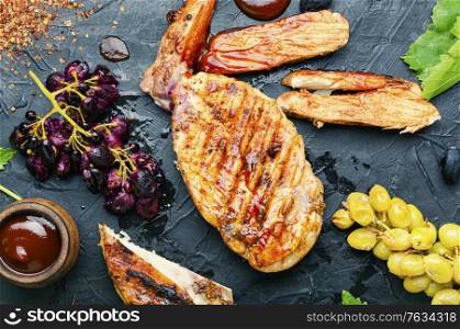 Sliced grilled chicken breast with grape sauce.Chicken fillets on slate concrete background. Chicken roasted steak with grapes