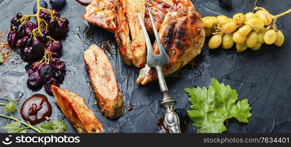 Sliced grilled chicken breast with grape sauce.Chicken fillets on slate concrete background. Grilled chicken breast