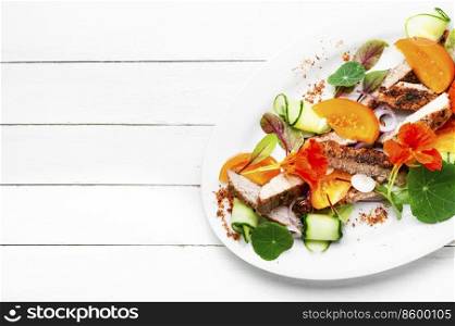 Sliced grilled steak with vegetable garnish and garnished with flowers. Meat salad, space for text. Sliced roasted steak with vegetables, salad