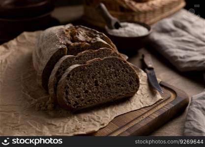 Sliced homemade bread with parchment paper on wood table. Bread at wooden tabletop as baking concept