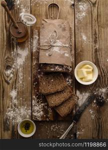 Sliced homemade rye bread on a wooden background with butter and honey