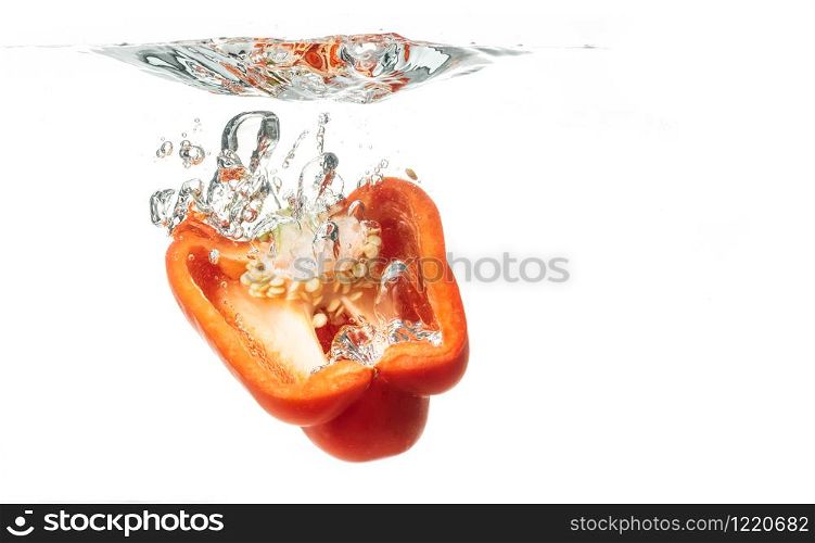 Sliced in half red bell pepper falls to the water, causing bubbles and scattered water. Healty food concept. Sliced in half red bell pepper falls to the water, causing bubbles and scattered water.