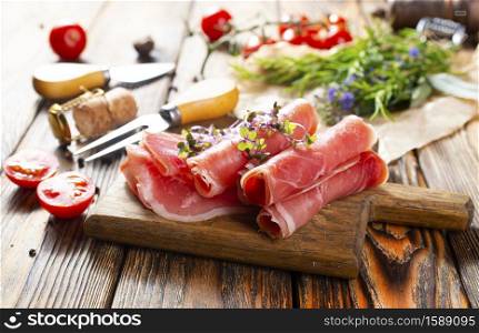 Sliced jamon on cutting board with tomato