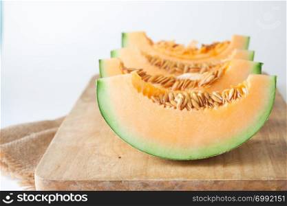 Sliced Japanese melons on wooden cutting board on white background