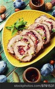 Sliced juicy meatloaf stuffed with plums. Autumn meat recipe.. Juicy porchetta or roulade with plums
