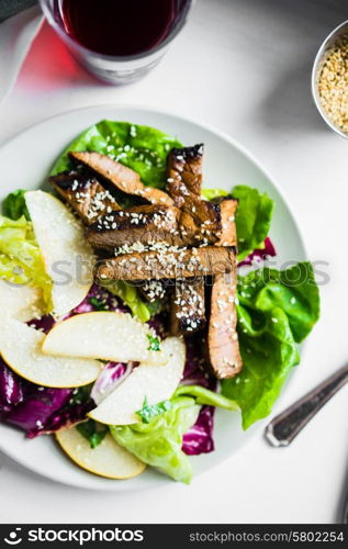 Sliced meat steak with green salad and pears