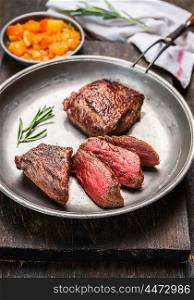 Sliced medium rare roasted meat beef steak in rustic plate on dark wooden background, close up