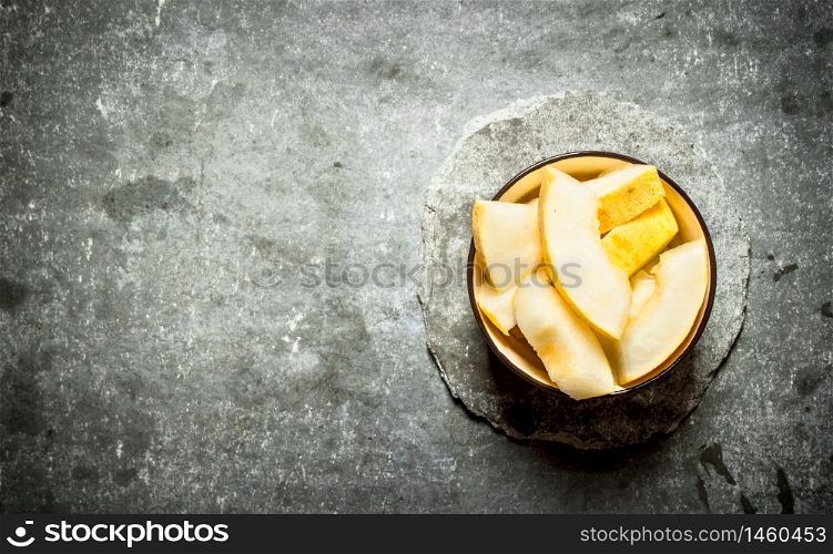 Sliced melon in a bowl. On a stone background.. Sliced melon in a bowl.