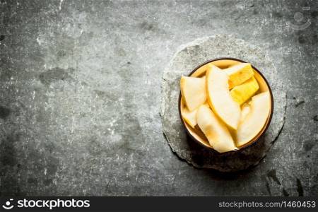 Sliced melon in a bowl. On a stone background.. Sliced melon in a bowl.