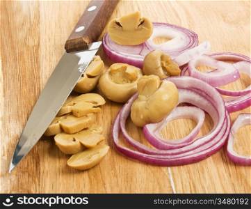 sliced mushrooms and onions on a cutting board