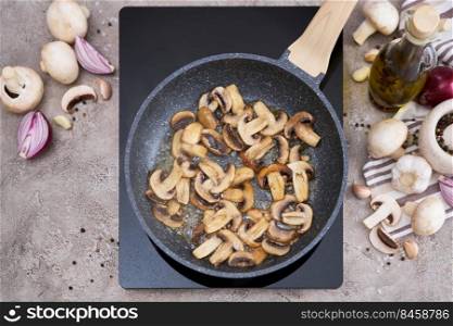 Sliced mushrooms in a frying pan on induction hob at domestic kitchen.. Sliced mushrooms in a frying pan on induction hob at domestic kitchen