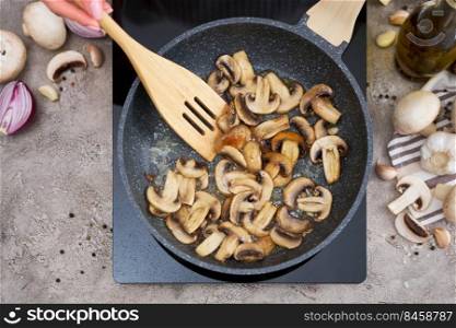 Sliced mushrooms in a frying pan on induction hob at domestic kitchen.. Sliced mushrooms in a frying pan on induction hob at domestic kitchen