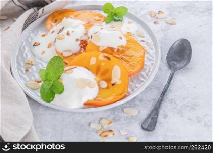 Sliced persimmon with yogurt and almonds. Healthy food concept on light background