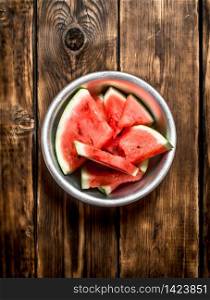 Sliced pieces of watermelon in the bowl. On wooden background.. Sliced pieces of watermelon in the bowl.