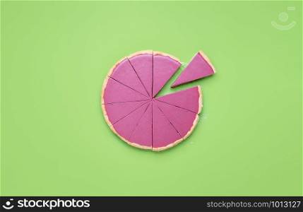 Sliced pink chocolate pie and one-piece separated, on green table. Flat lay of ruby chocolate mousse in pie crust cut in slices. Christmas desserts.