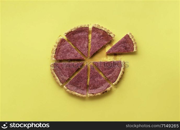Sliced pink pie with cranberry curd and one slice separated on a yellow background. Flat lay of delicious berries tart. Thanksgiving pink pie.