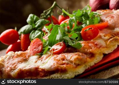 sliced pizza with arugula and cherry tomatoes on wooden table