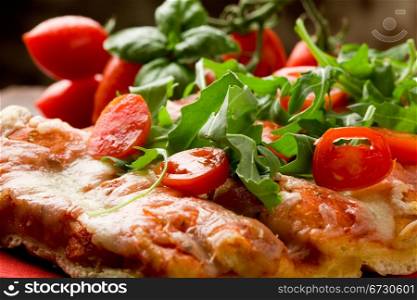 sliced pizza with arugula and cherry tomatoes on wooden table