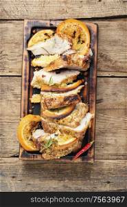 Sliced pork meat stuffed with oranges.Roasted meat on the kitchen board.. Baked meat in oranges