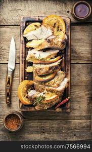 Sliced pork meat stuffed with oranges.Roasted meat on the kitchen board.. Baked meat in oranges