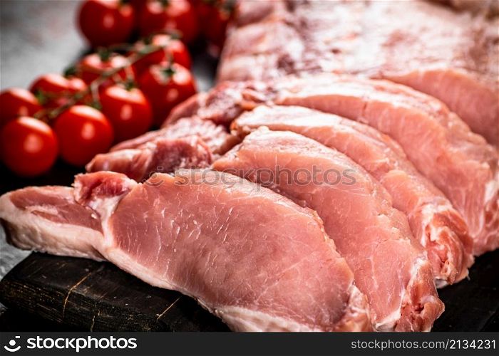 Sliced pork raw on a cutting board. On a rustic dark background. High quality photo. Sliced pork raw on a cutting board.