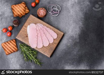 Sliced prosciutto ham on wooden cutting board. Black concrete background. Sliced ham on wooden background. Fresh prosciutto. Pork ham sliced