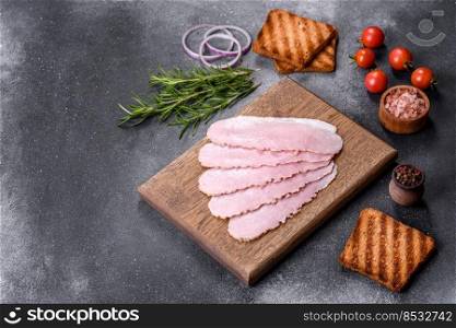 Sliced prosciutto ham on wooden cutting board. Black concrete background. Sliced ham on wooden background. Fresh prosciutto. Pork ham sliced