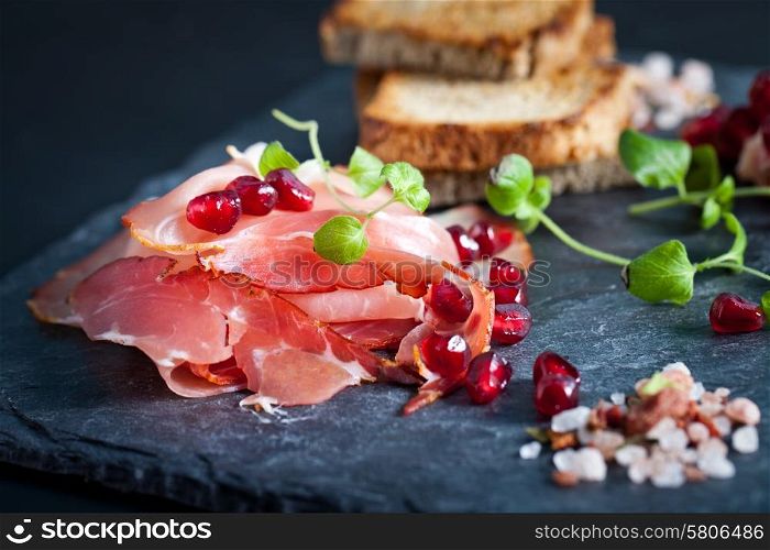 Sliced prosciutto with herbs and pomegranate seeds