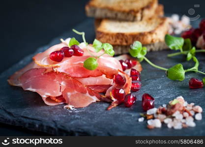 Sliced prosciutto with herbs and pomegranate seeds