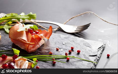 Sliced prosciutto with herbs and pomegranate seeds