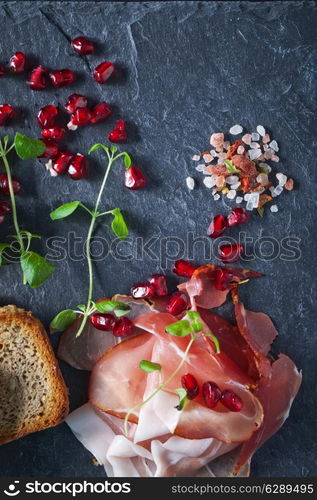 Sliced prosciutto with herbs and pomegranate seeds