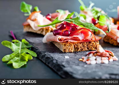 Sliced prosciutto with herbs and pomegranate seeds