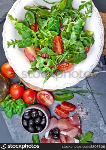 Sliced prosciutto with salad and olive