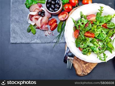 Sliced prosciutto with salad and olive