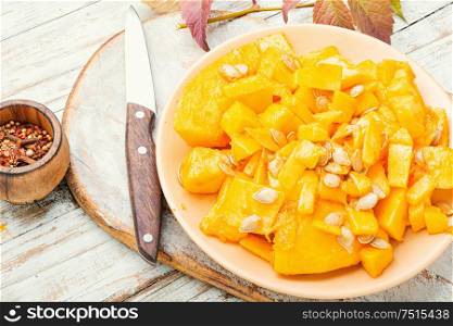 Sliced pumpkin on wooden background.Autumn vegetarian cooking. Sliced pumpkin on a plate