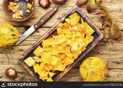 Sliced pumpkin on wooden background.Autumn vegetarian cooking. Sliced pumpkin on kitchen board