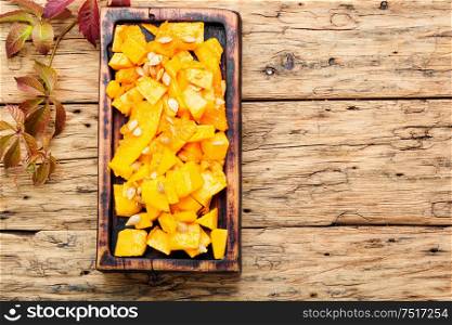 Sliced pumpkin on wooden background.Autumn vegetarian cooking.Space for text. Sliced pumpkin on kitchen board