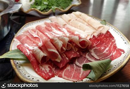 Sliced raw beef for cooking on table with hot pot