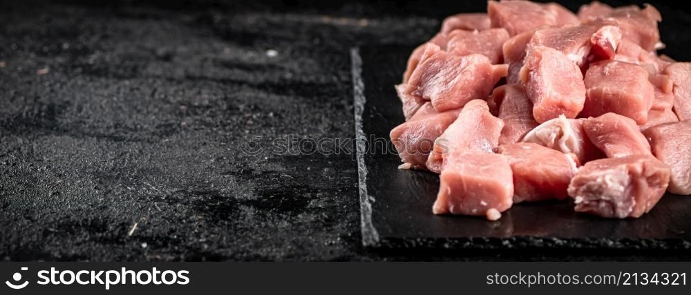 Sliced raw pork on a stone board. On a black background. High quality photo. Sliced raw pork on a stone board.