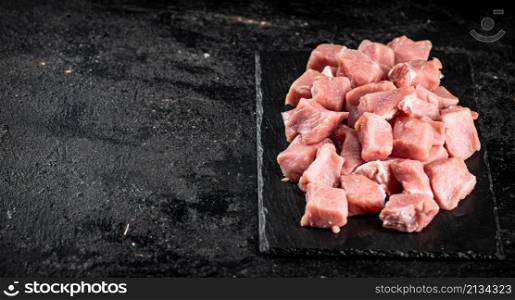 Sliced raw pork on a stone board. On a black background. High quality photo. Sliced raw pork on a stone board.