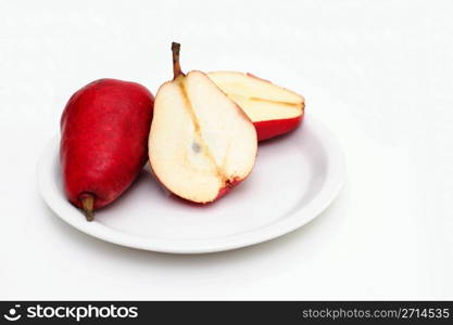 Sliced Red Pear. Red pears on a white saucer on pear is sliced in half showing the core and seeds