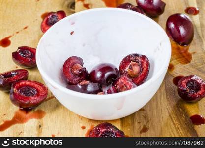 sliced red sweet cherries on a white wooden table, preparing cherries for use in cooking. sliced red sweet cherries