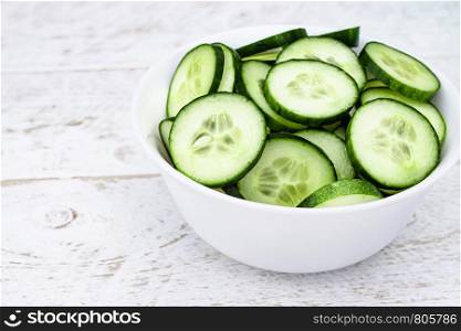 Sliced rings of green cucumbers in a white plate on a white background. Close-up.. Sliced rings of green cucumbers in a white plate on a white background.