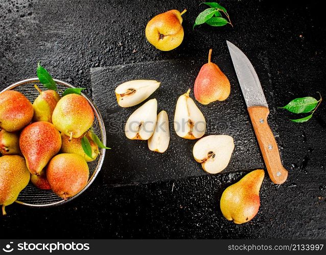 Sliced ripe pear with a knife. On a black background. High quality photo. Sliced ripe pear with a knife.