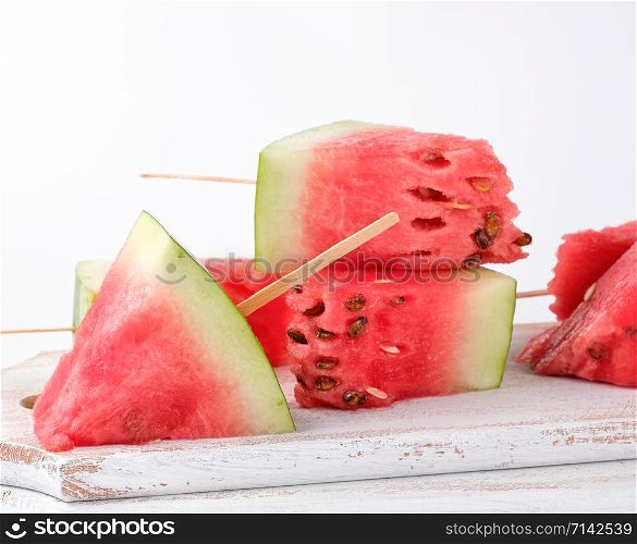 sliced ripe red watermelon with seeds on a wooden white cutting board, summer berry