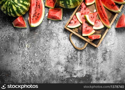 Sliced ripe watermelon on a wooden tray. On a rustic background.. Sliced ripe watermelon on a wooden tray.