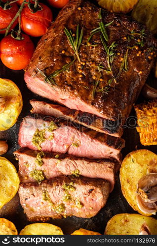 Sliced Roast beef on cutting board with grilled vegetables